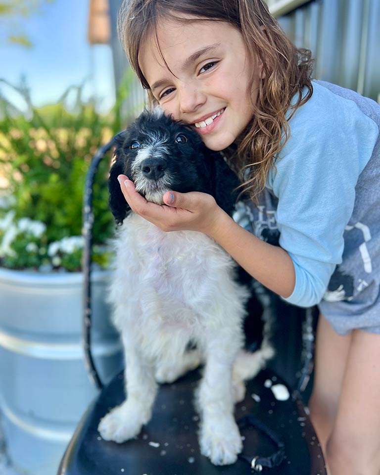 Young girl hugging a puppy sitting on a black chair