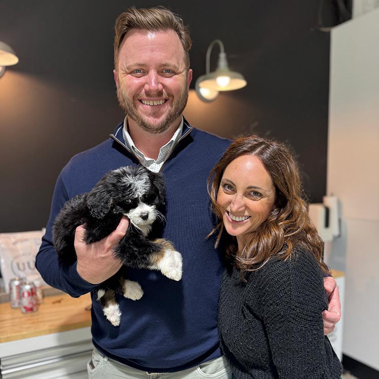 Couple holding their newly adopted Sheepadoodle puppy and wondering about Sheepadoodle energy levels