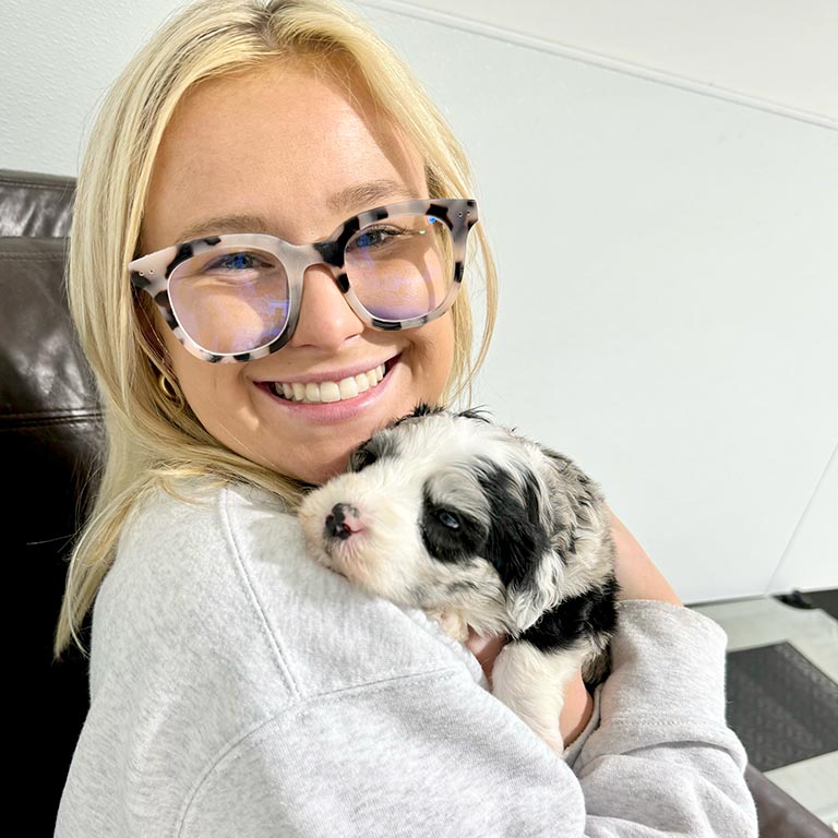 Young dog owner with glasses holding her new puppy and wondering why do dogs dream