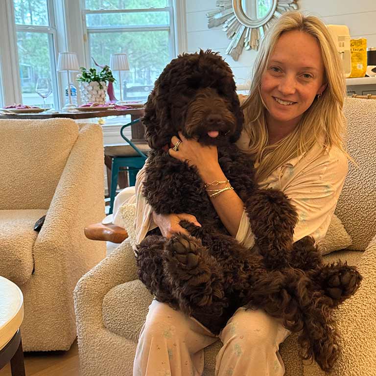 Owner holding her adult doodle on her laps, learning how to prevent separation anxiety in dogs