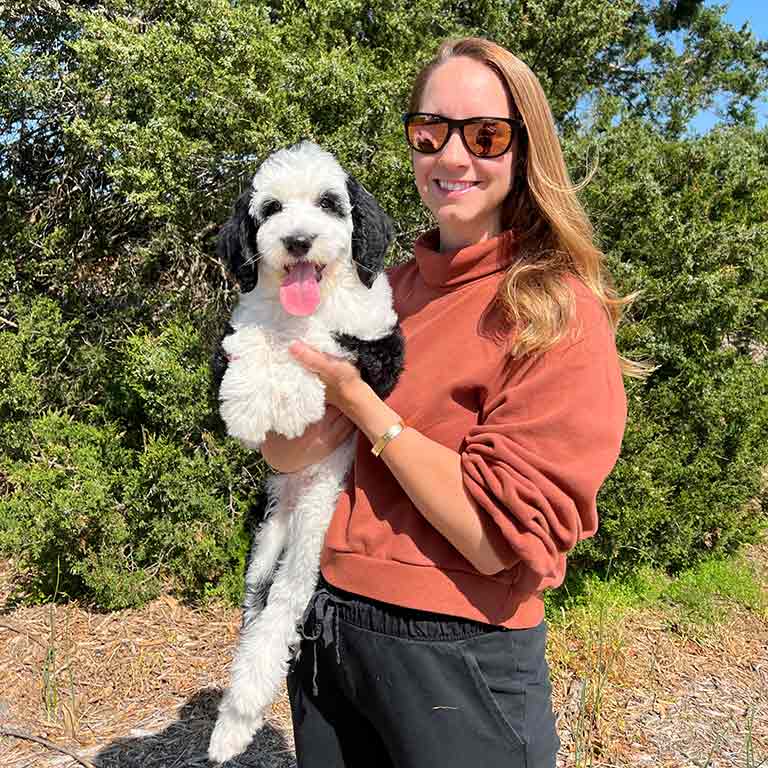 Woman holding her puppy outside, worried about dog motion sickness on the way home.