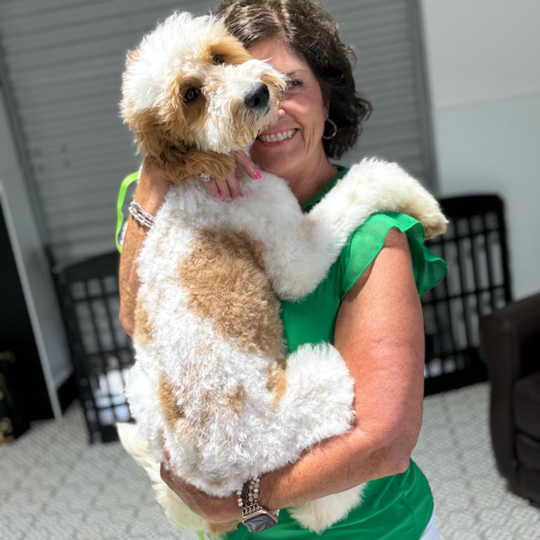 Trainer at Double U Doodles holding one of their dogs in her arms